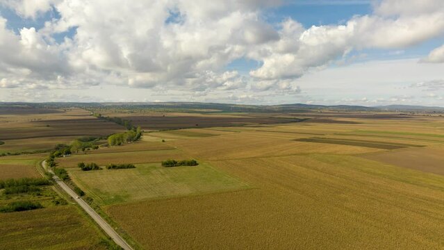 Cinematic aerial hyperlapse over golden farmlands with fast moving clouds in Romania.