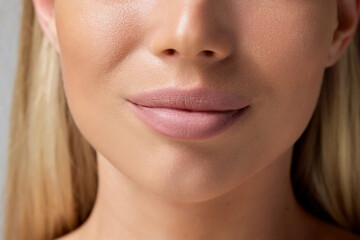 Fototapeta premium Cropped close-up image of plump female lips, perfect chin isolated on grey background. Cosmetology injection