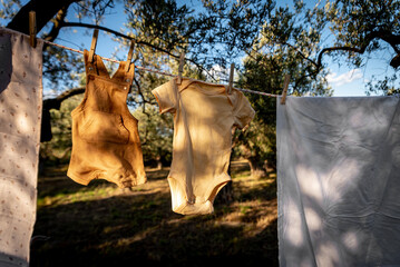 Baby clothes on clothesline drying in garden. Newborn childhood concept