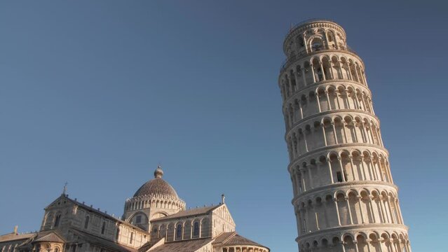 still shot with one bird crossing to the right in front of the leaning tower of pisa in tuscany italy during the morning and golden hour
