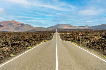 Road in volcanic arid landscape of Timanfaya National Park, Lanzarote, Canary Islands, Spain