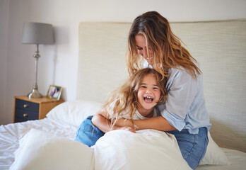 Mom and child on the bed playing together, having fun and laughing. Portrait of mother and daughter in bedroom, smiling while woman tickle young girl. Family, love and laughter in morning at home - obrazy, fototapety, plakaty