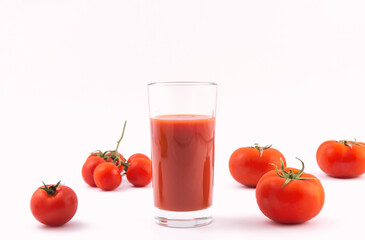 Tomato juice in a glass and ripe tomatoes on a white background
