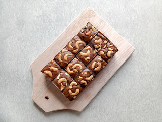 Dessert, Homemade chocolate brownie with cashew nuts on wooden plate. Chocolate brownie cake isolated on white background. Top view.