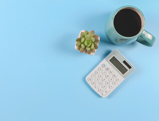  flat lay of blue calculator, blue cup of  black coffee  and succulent plant pot on blue  background.