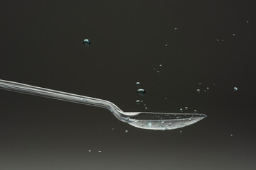 lastic spoon with water drops frozen at high speed showing surface tension and droplet splash...