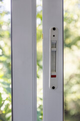 Close-up of a double-glazed balcony frame with a latch and fastening for safe ventilation. Single-sided window handle. House door and window repair concept