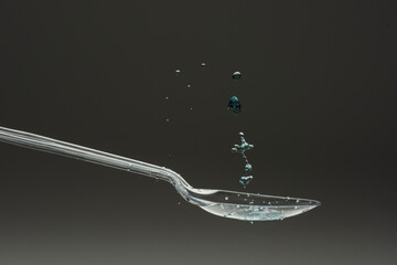 lastic spoon with water drops frozen at high speed showing surface tension and droplet splash...
