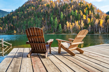 Two comfortable wooden sun loungers against the backdrop of colorful mountains with emerald lake