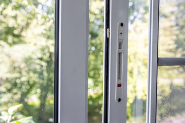 Close-up of a double-glazed balcony frame with a latch and fastening for safe ventilation. Single-sided window handle. House door and window repair concept