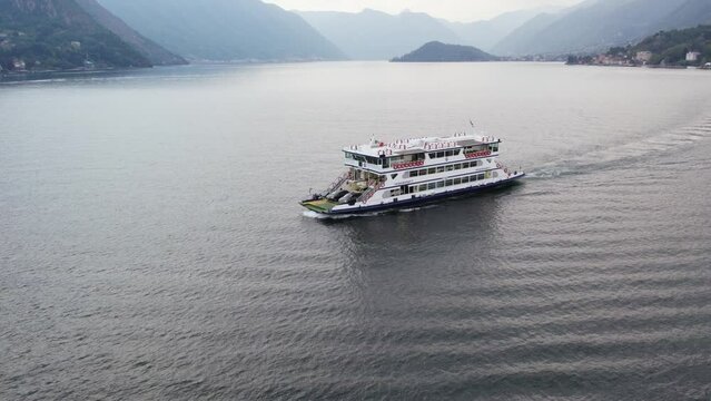 Ferry Boat Carrying Cars Sailing Across The Lake Como To Bellagio Comune in Italy. - aerial