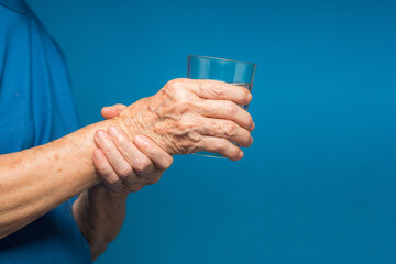 Close-up of hands senior woman trying to hold a glass of water