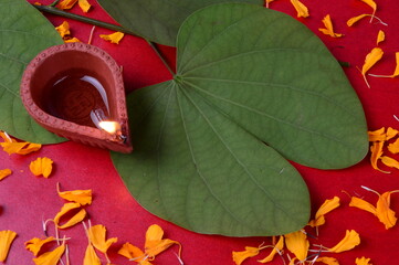 Indian Festival Dussehra, showing golden leaf and flowers with traditional diya on red background....