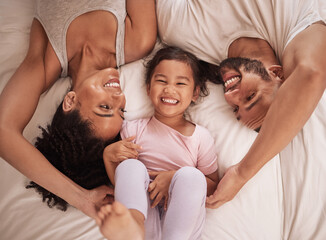 Above, family and child happy on bed smile, laugh and bonding on weekend. Mom, dad and parents with kid in pajamas enjoying quality time, being playful and fun together in bedroom in the morning.