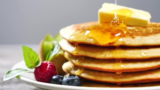Maple syrup being poured on pancakes for breakfast 