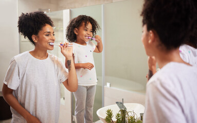 Mirror reflection of mom and girl brushing teeth together while bonding, having fun and enjoy...