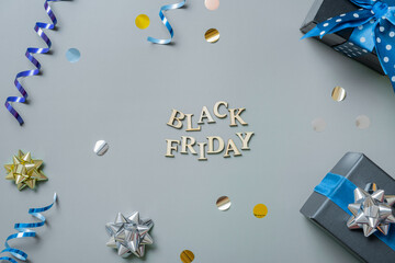 Black friday text with gifts and festive tinsel flat lay
