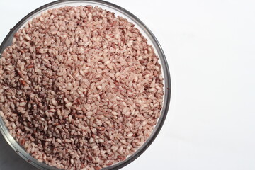 Uncooked red rice grain on a bowl, Amon rice grain on white background