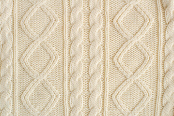 knitted milk sweater with a pattern of braids close-up. Knitted natural wool yarn texture. Texture