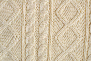 Fototapeta premium knitted milk sweater with a pattern of braids close-up. Knitted natural wool yarn texture. Texture