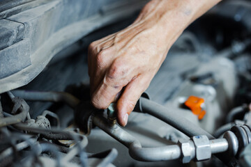 Obraz premium An auto mechanic works with a car engine in the mechanics' garage. Car repair close-up. An authentic close-up shot of an auto mechanic's hands.