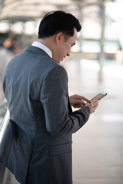 Asian businessman using mobile phone outside of office