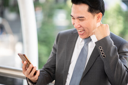 Asian businessman using mobile phone outside of office