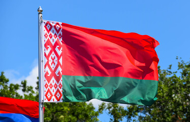 The flag of Belarus is a rectangular banner, which consists of two horizontal stripes of red and green on a background of blue sky in the afternoon in summer