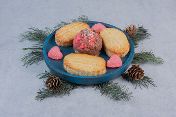 Two kinds of cookies and heart shaped candies on blue plate