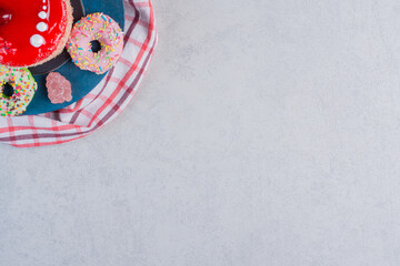Fototapeta na wymiar Fruit cake, donuts and marmalades on blue board