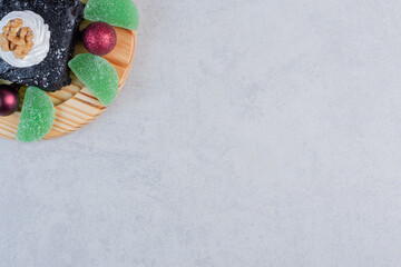 Chocolate brownie with marmalades and baubles on wooden plate