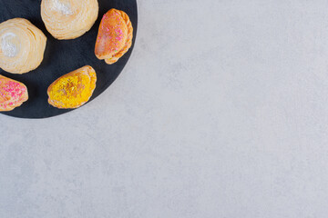Assortment of delicious cookies and marmalades on black board