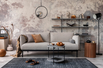 Loft style of modern apartment with grey design sofa, coffee table, bookstand, pedant lamp, carpet, decoration and elegant accessories . Concrete grunge wall. Template.	