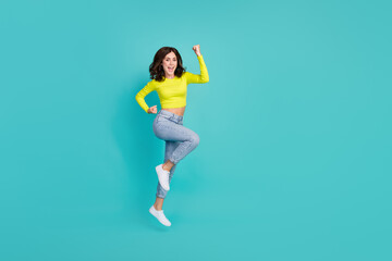 Fototapeta na wymiar Full length portrait of delighted cheerful person jumping raise fists triumph luck isolated on turquoise color background