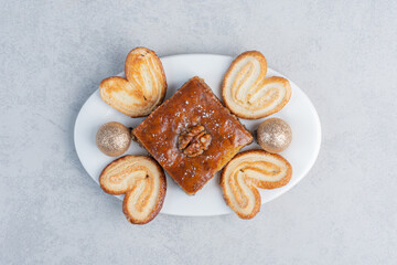 Flaky cookies and a bakhlava on a platter with a bauble on marble background