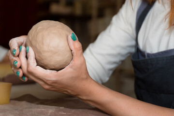 Close up shot of  hands sculpling mug from wet clay in pottery workshop