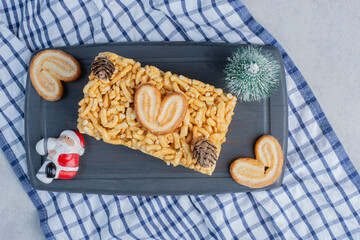 Biscuit cake with flaky cookies and christmas ornaments on a board on marble background