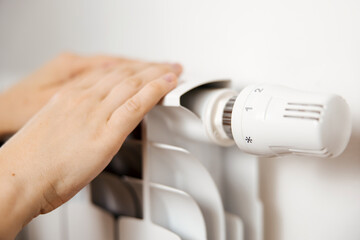 Woman hands on white heating radiator, close up view. It is cold, person warms up. Central heating...