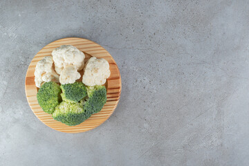 A wooden board with broccoli and cauliflower