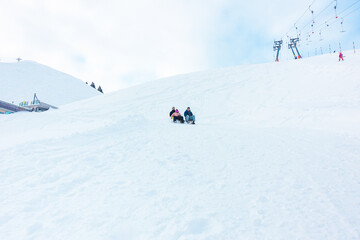 Fototapeta na wymiar Crazy happy friends having fun with sledding on snow high mountains