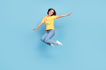 Fototapeta na wymiar Full length portrait of excited crazy person jumping arms wings flying isolated on blue color background