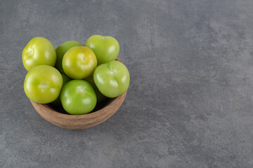 Fresh green tomatoes in wooden bowl