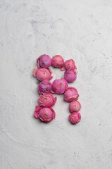 letter R outlined with pink flowers on a white background

