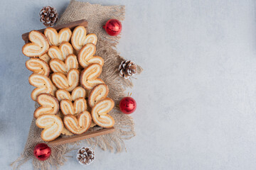 Flaky cookies piled in a wooden basket and surrounded with christmas decorations on marble background