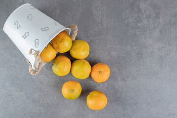 Delicious ripe tangerines out of bucket on marble background