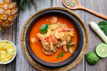 Pineapple and shrimp red curry - Thai authentic food called Kang Kua Supparos at top view on wood table