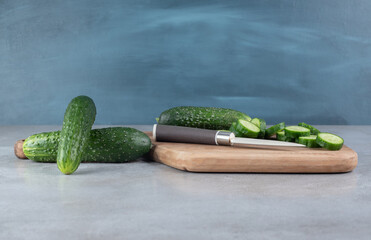 Fresh cucumbers with knife on a wooden board