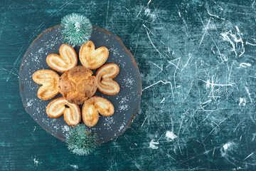 Delicious muffin and cookies on a dark wooden board