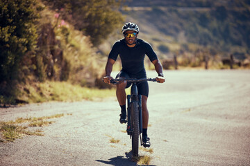 Fitness, mountain and man cycling on a bicycle in summer for exercise, training and cardio workout on the road. Lifestyle, wellness and strong cyclist enjoys riding his mountain bike alone outdoors