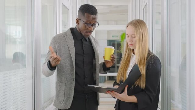 Two students diverse race and nationality work and study together, discuss their papers, diploma work. Multiethnic team in college, university. Couple of students walk in the hall and brainstorming